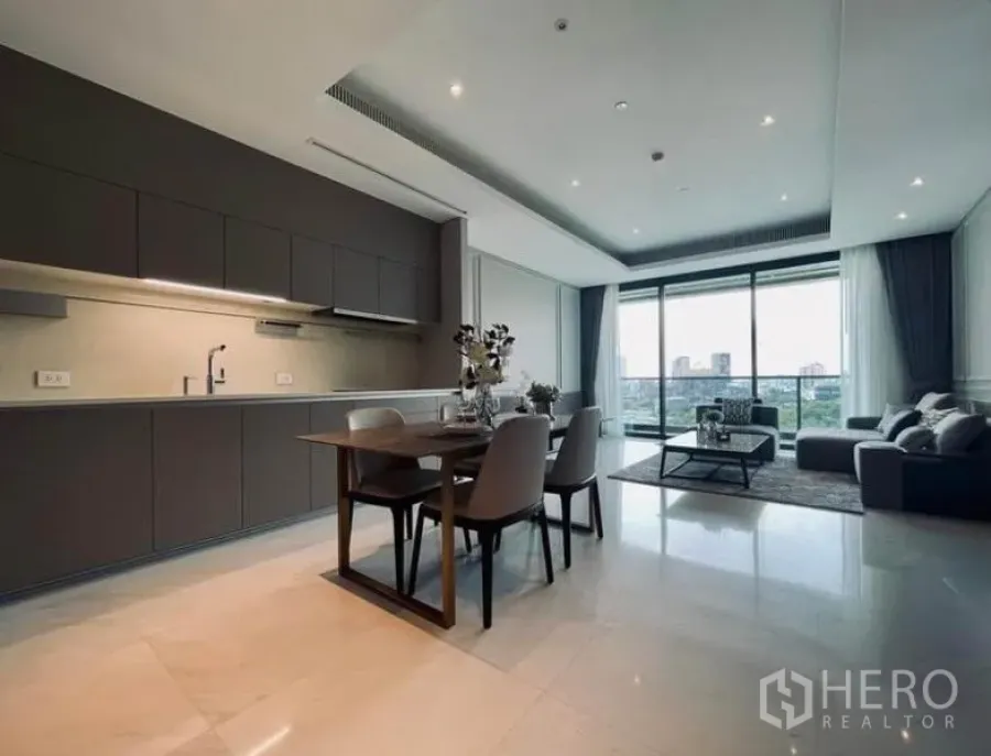 Condominium for rent in Pathum Wan, Bangkok - Open-plan living and dining area with sleek grey kitchen, marble-look floors, and balcony city view in a Pathum Wan condo.