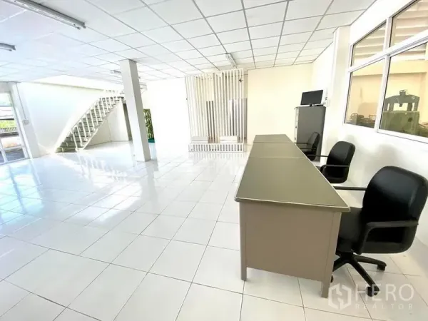 Warehouse for rent in Lam Luk Ka, Pathum Thani - Open-plan office zone with desks, partition feature wall and windows to the warehouse floor.