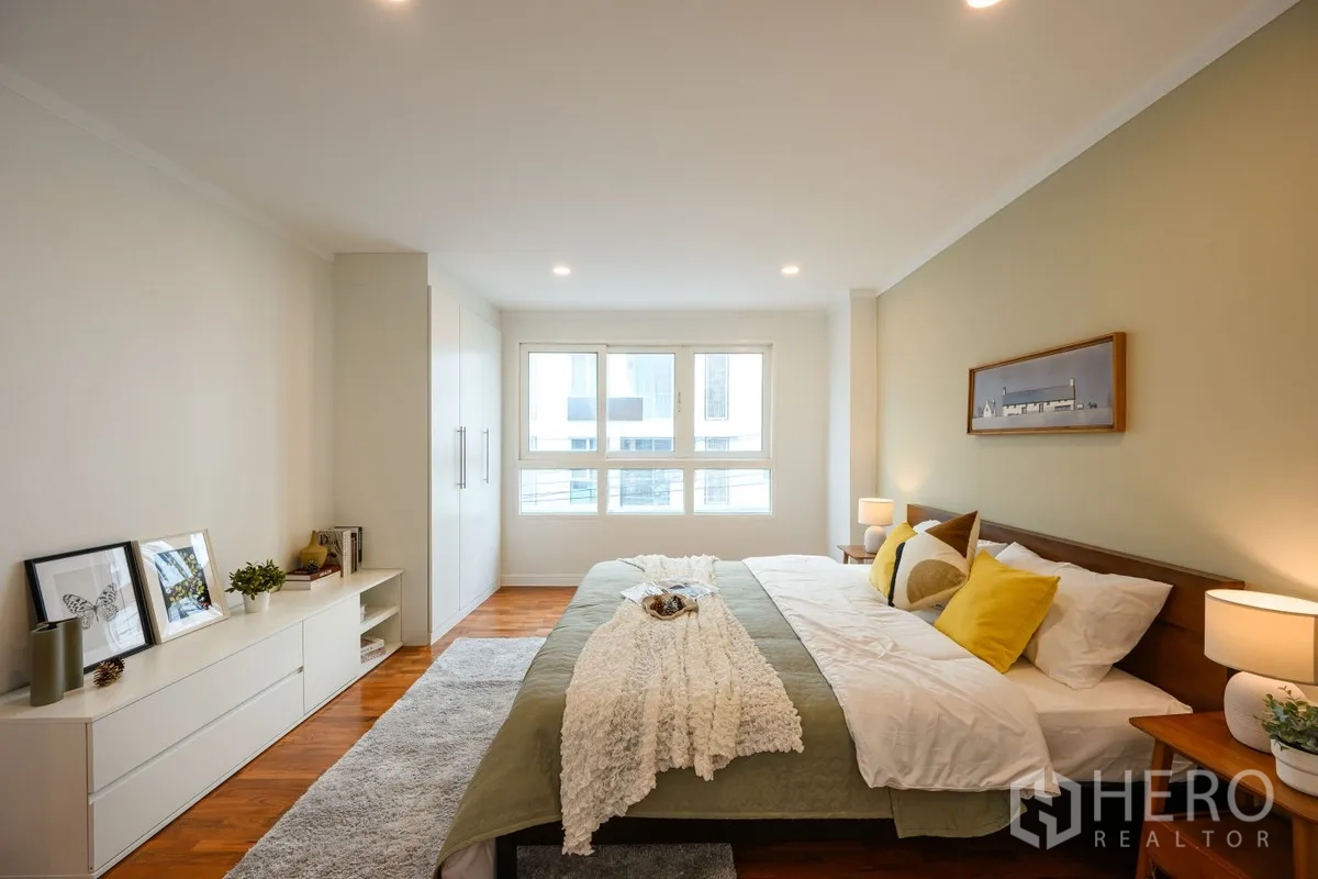 Condominium for sale in Watthana, Bangkok - Large bedroom with king bed, bedside tables, big window, and built-in wardrobe.