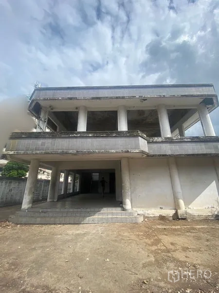 Office Space for sale in Wang Thonglang, Bangkok - Wide front view of the office building and open yard under a cloudy sky.