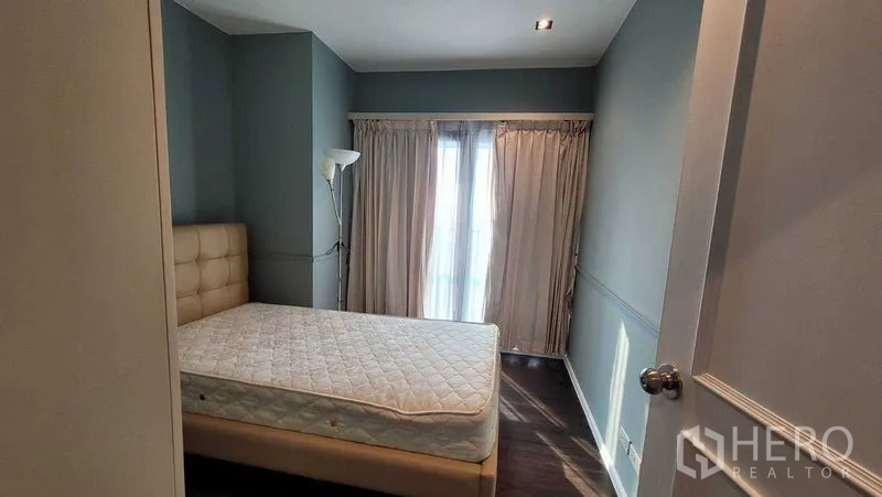 คอนโด ให้เช่าในKhlong Toei, Bangkok - ห้องนอนอบอุ่น เตียงบุหนัง พื้นไม้ และผ้าม่านสูงจรดเพดานเปิดสู่ระเบียง