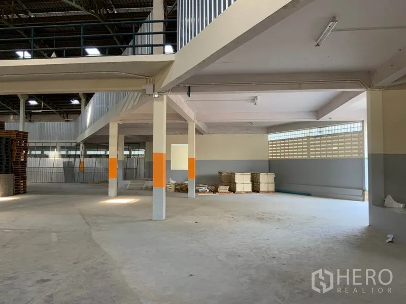 Warehouse for rent in Khlong Sam Wa, Bangkok - Bright warehouse interior with concrete floor, support columns and partial mezzanine for storage.
