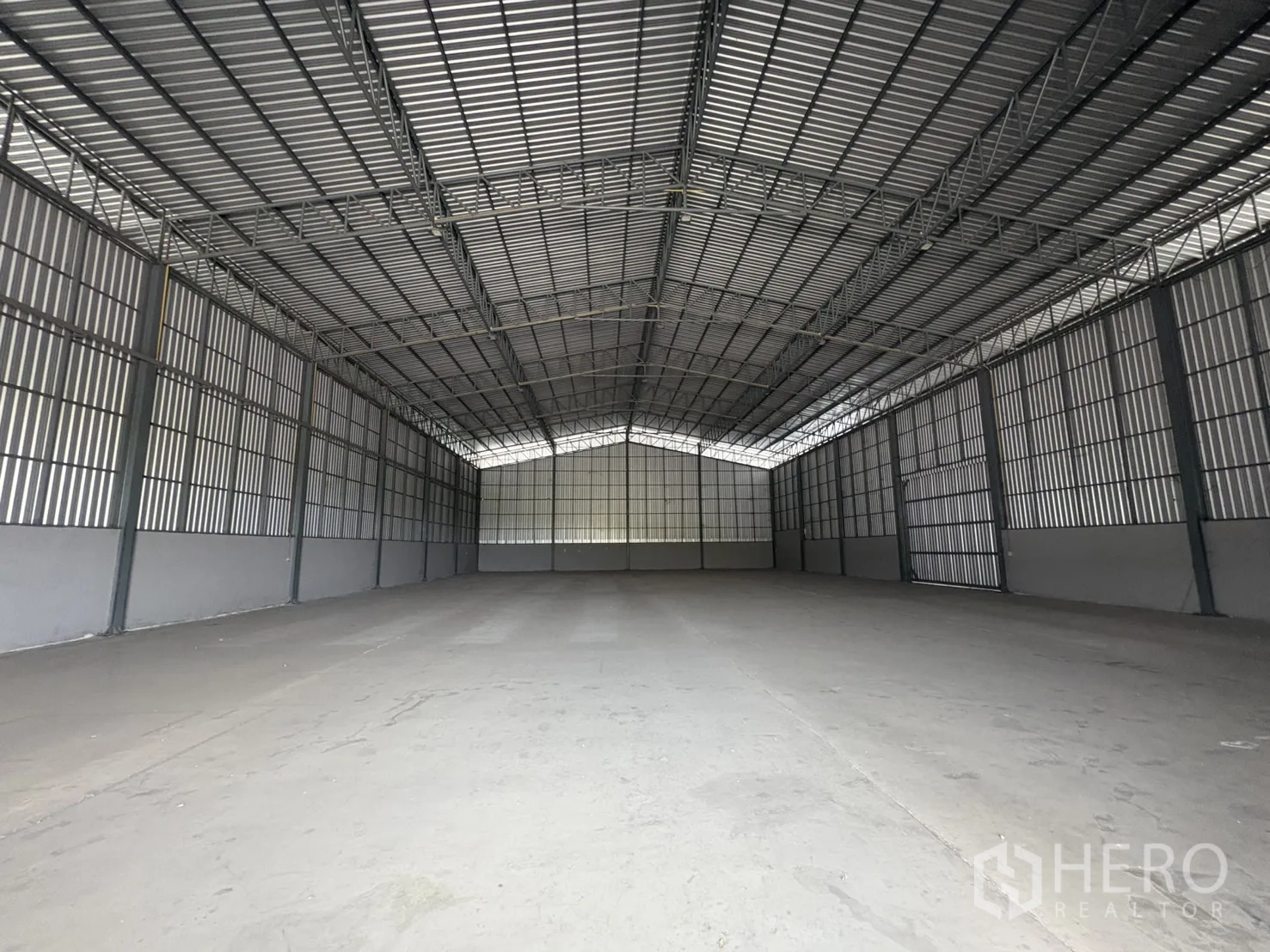 คลังสินค้า ให้เช่าในMueang Samut Prakan, Samut Prakan - มุมมองยาวของพื้นโกดังโล่ง ผนังเมทัลชีทสูงและเพดานสูง.