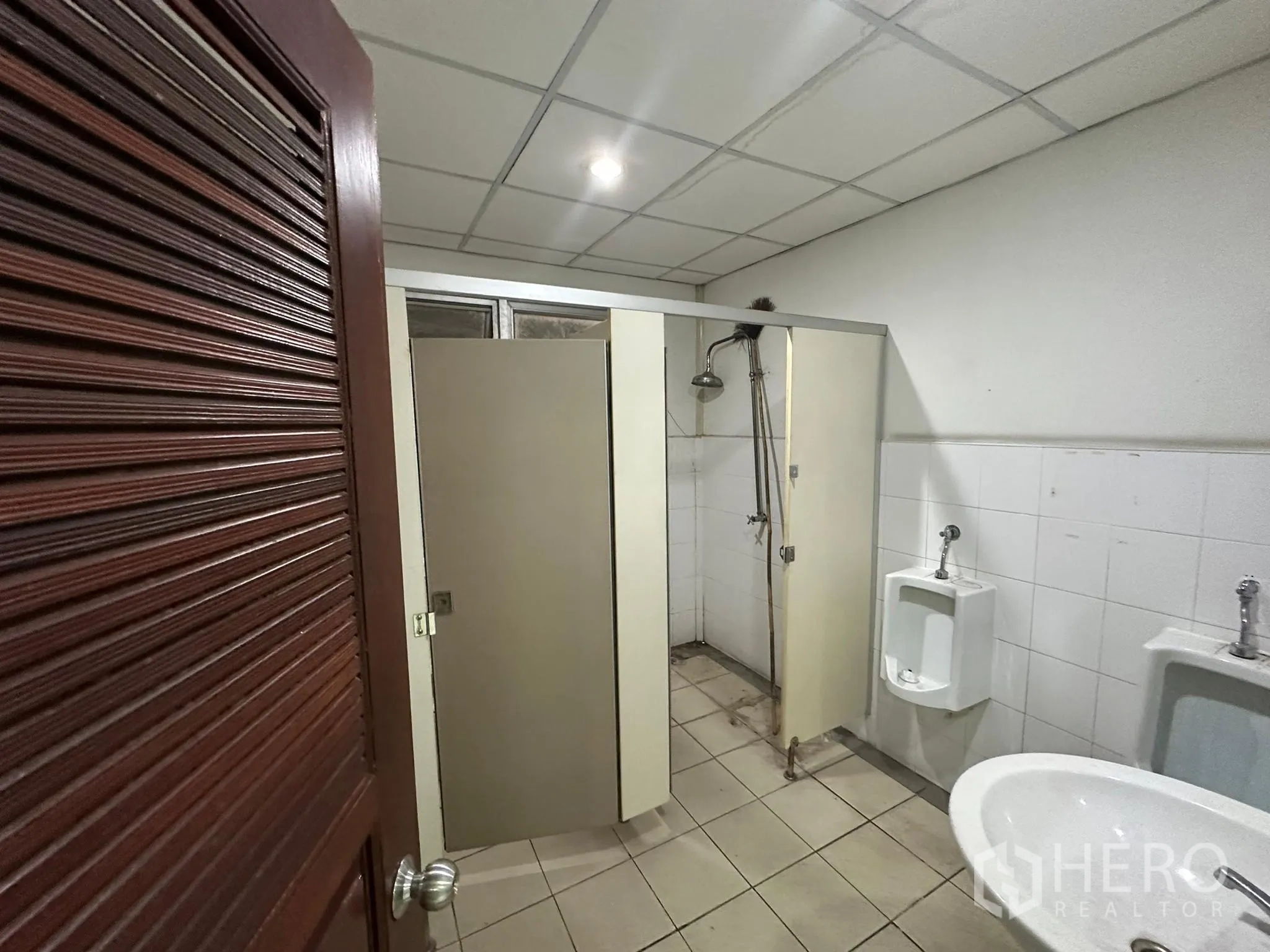 Warehouse for rent in Huai Khwang, Bangkok - Staff restroom with shower, urinals and tiled walls.