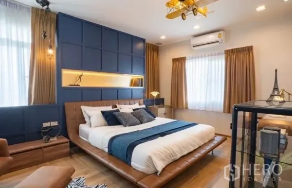 Detached House for rent in Bang Phli, Samut Prakan - Stylish bedroom with navy panel feature wall, platform bed and airplane-style ceiling light.
