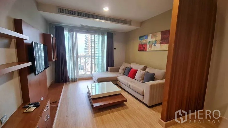 Condominium for rent or sale in Watthana, Bangkok - Dining zone with glass-top table and wooden chairs under decorative pendant lights facing the balcony.