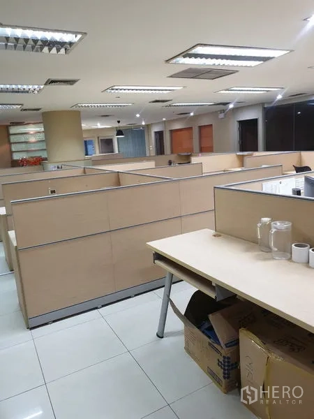 Office Space for rent - Open-plan workspace with multiple beige cubicles and overhead lighting.