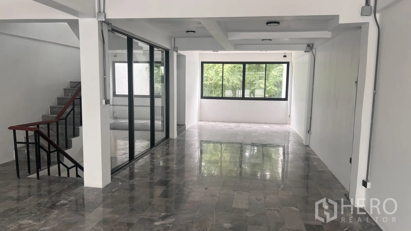 โฮมออฟฟิศ for rent or sale in Phra Khanong, Bangkok - พื้นที่โล่งยาวปูพื้นหินอ่อนพร้อมผนังกระจกบานเลื่อนข้างบันได.