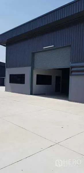 Warehouse for rent in Lat Lum Kaeo, Pathum Thani - Modern steel-clad warehouse with a large roller shutter and a wide concrete yard.