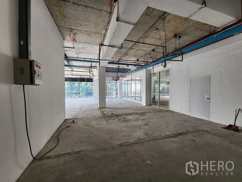 Retail Space for rent in Sathon, Bangkok - Unfinished retail interior with columns, electrical panel, service door and glass wall to exterior.
