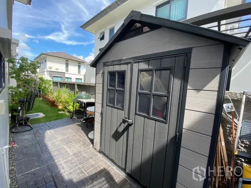 Detached House for rent in Bang Phli, Samut Prakan - Neat side yard with a storage shed beside paved paths and green lawn.