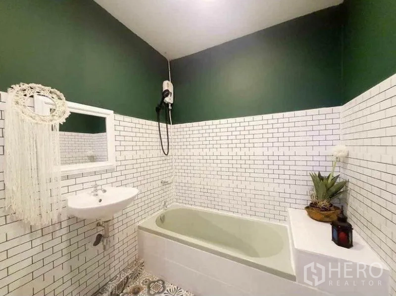 Detached House for rent in Pathum Wan, Bangkok - Bathroom with white subway tiles, green upper walls, bathtub and electric shower.