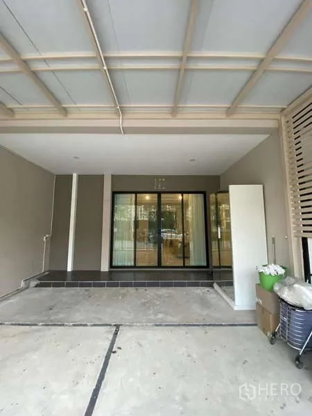 Townhouse for rent in Bang Kapi, Bangkok - Covered front carport with ceiling lights and sliding glass entry to the house.