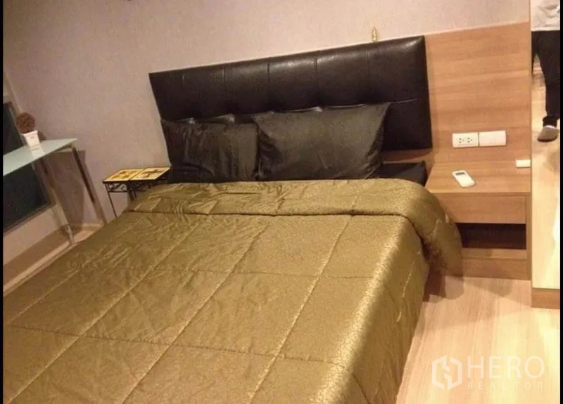 公寓 出售在Phaya Thai, Bangkok - 卧室配软包床头、床头柜，金色被套与木地板。