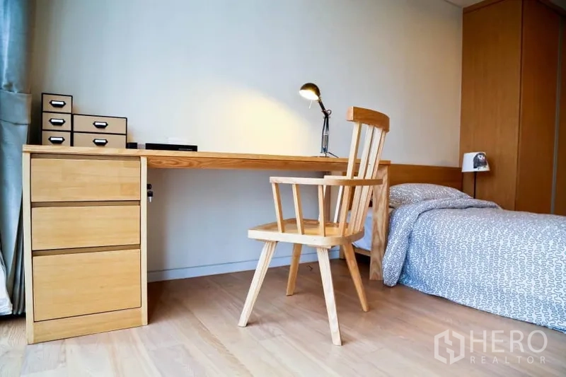 Condominium for rent in Watthana, Bangkok - Spacious master bedroom with tall windows, wood floors and bedside lamps.