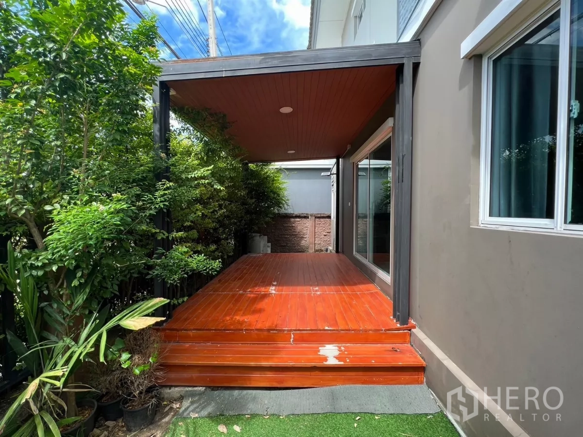 Detached House for rent in Suan Luang, Bangkok - Side wooden terrace under a roof beside lush greenery and a sliding glass door