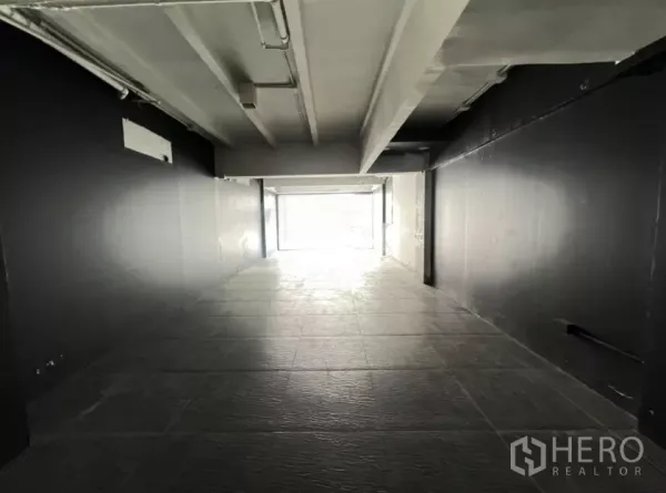 零售空间 出租在Watthana, Bangkok - 深进式零售空间，黑墙、顶灯与纹理瓷砖地面。