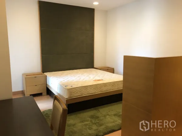 คอนโด ให้เช่าในKhlong Toei, Bangkok - ห้องนอนมาสเตอร์สว่าง พนักเตียงบุผ้า โต๊ะข้างเตียง และพรมสีเขียวในคอนโดกรุงเทพฯ