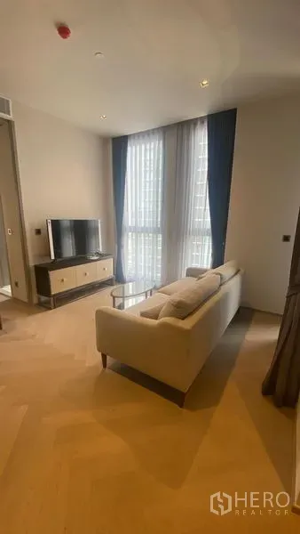 Condominium for rent - Cozy lounge with sofa facing TV, tall windows and warm wood floors.