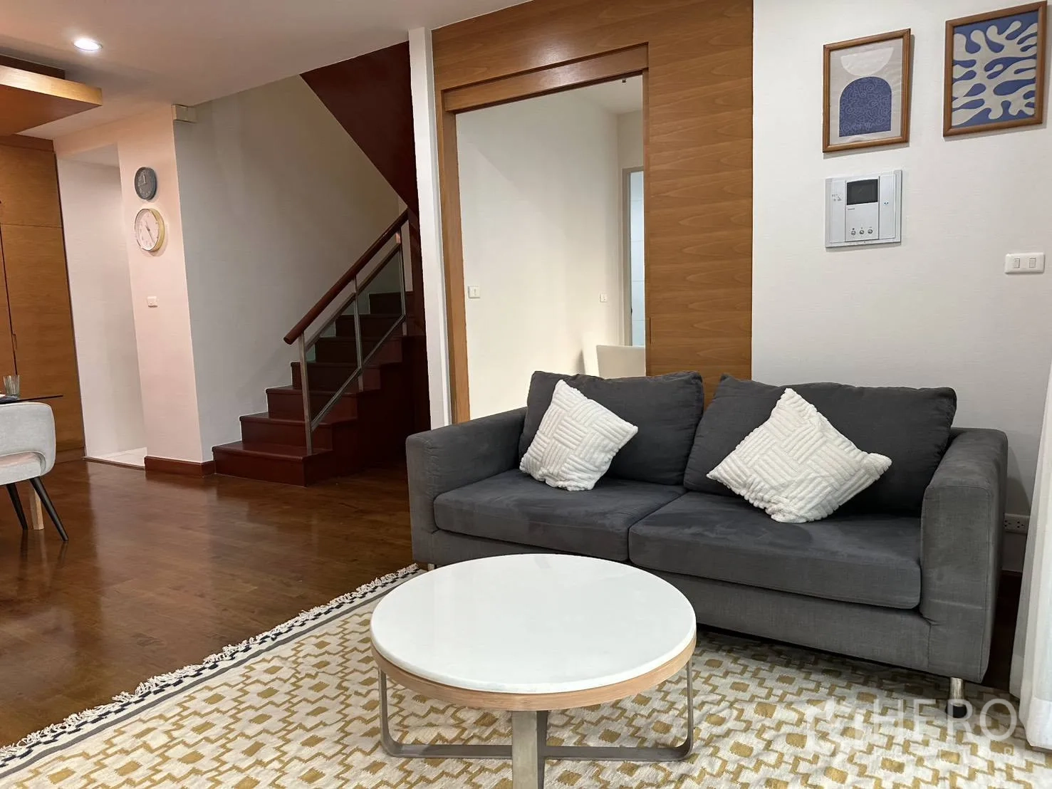 Condominium for rent in Watthana, Bangkok - Cozy living area with gray sofa, coffee table, and staircase.