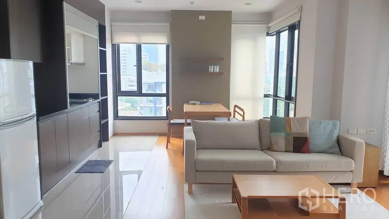 คอนโด ให้เช่าในPhaya Thai, Bangkok - ห้องนั่งเล่นโปร่งสว่าง พร้อมครัวบิลต์อิน พื้นไม้ และหน้าต่างวิวเมืองในคอนโดอารีย์