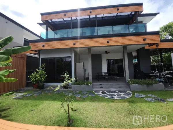 Detached House for rent in Bang Phli, Samut Prakan - Rear facade featuring a large balcony, lawn and sliding glass doors.