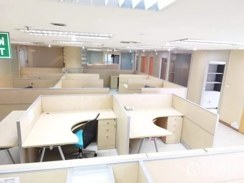 สำนักงาน ให้เช่า - ชั้นสำนักงานแปลนเปิดสว่าง มีเวิร์กสเตชันหลายชุดและป้ายทางออก