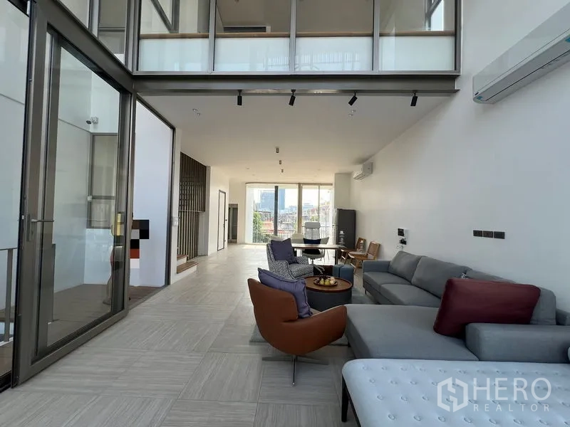 สำนักงานที่บ้าน ให้เช่าหรือขายในChatuchak, Bangkok - พื้นที่นั่งเล่นและรับประทานอาหารแบบเพดานสูง พร้อมชุดโซฟาและหน้าต่างบานใหญ่