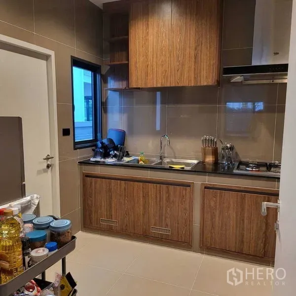 Detached House for rent in Mueang Pathum Thani, Pathum Thani - Separate Thai kitchen with wood cabinetry, gas hob and sink