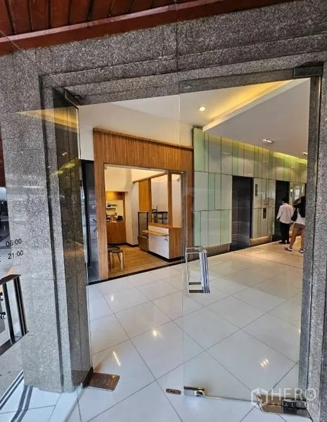 零售空间 出租在Watthana, Bangkok - 透过玻璃门看到带木质饰面的零售摊位，旁边是电梯厅