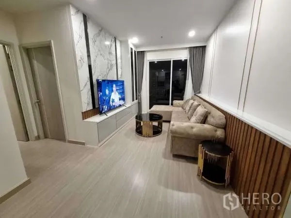 公寓 出租 - 宽敞起居区，L形沙发、电视柜与落地推拉门。