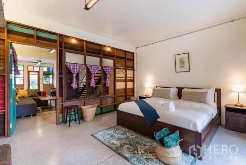 Townhouse for rent in Pathum Wan, Bangkok - Airy bedroom with wooden bed, built-in partition and soft lighting.