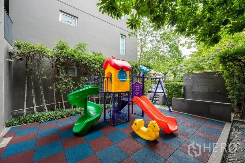 คอนโด ขาย - สนามเด็กเล่นกลางแจ้ง มีสไลเดอร์สีสันสดใสและพื้นยางลายตาราง