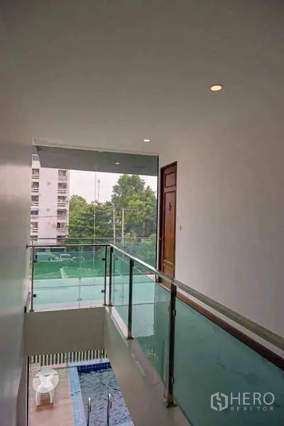 บ้าน ขายในLat Phrao, Bangkok - โถงชั้นบน ราวกันตกกระจก มองเห็นสระว่ายน้ำและชุมชนโดยรอบ