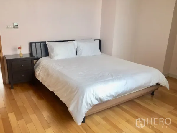 คอนโด ให้เช่าในKhlong Toei, Bangkok - ห้องนอนมาสเตอร์กว้าง พร้อมชุดผ้าปูสีขาว โต๊ะข้างเตียง และพื้นไม้