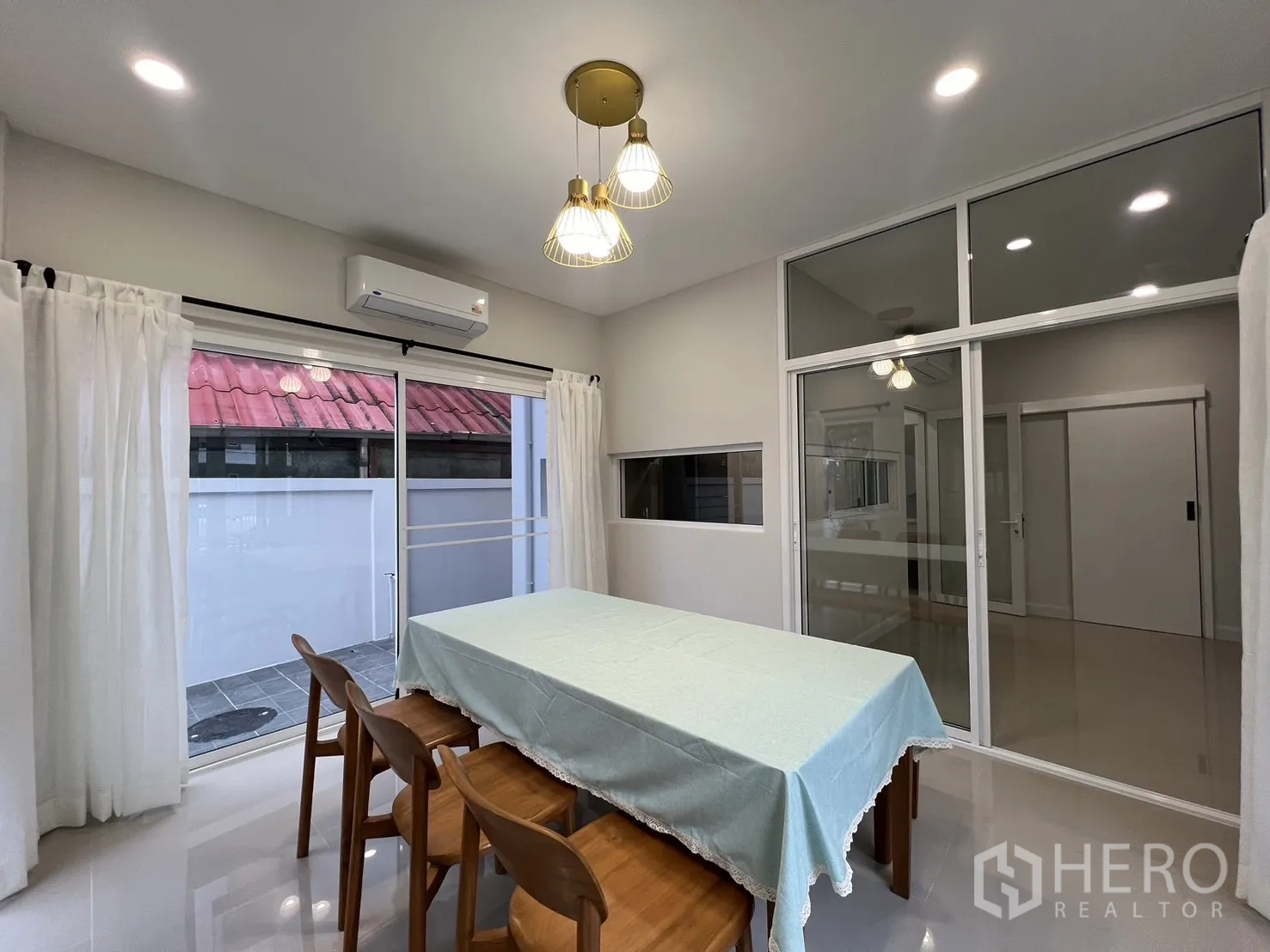 Detached House for rent in Saphan Sung, Bangkok - Dining area with glass partition to the living room and white curtains.