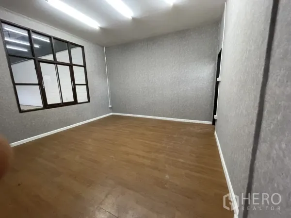 คลังสินค้า ให้เช่าในLam Luk Ka, Pathum Thani - ห้องออฟฟิศปูพื้นลายไม้ ผนังลายเทา มีช่องหน้าต่างมองเข้าโกดัง.