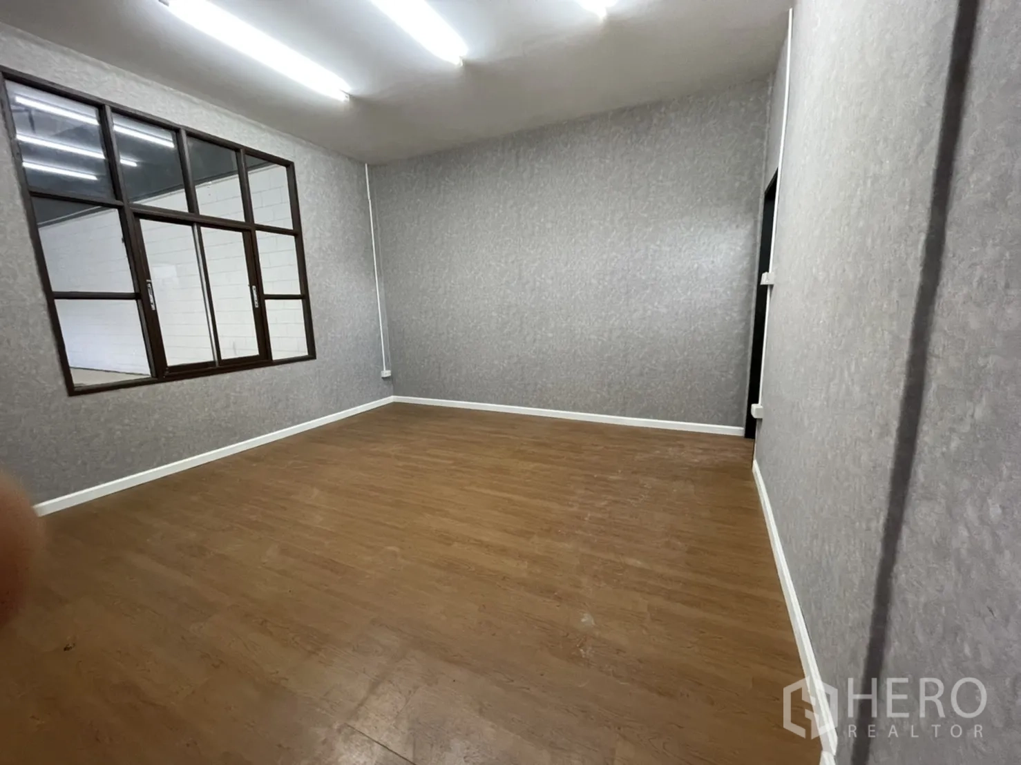 คลังสินค้า ให้เช่าในLam Luk Ka, Pathum Thani - ห้องออฟฟิศปูพื้นลายไม้ ผนังลายเทา มีช่องหน้าต่างมองเข้าโกดัง.