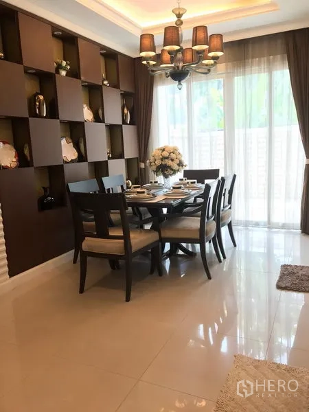 Townhouse for rent or sale in Bang Kho Laem, Bangkok - Bright dining area with six-seat wooden table, chandelier, built-in display shelves and sheer curtains to the patio.
