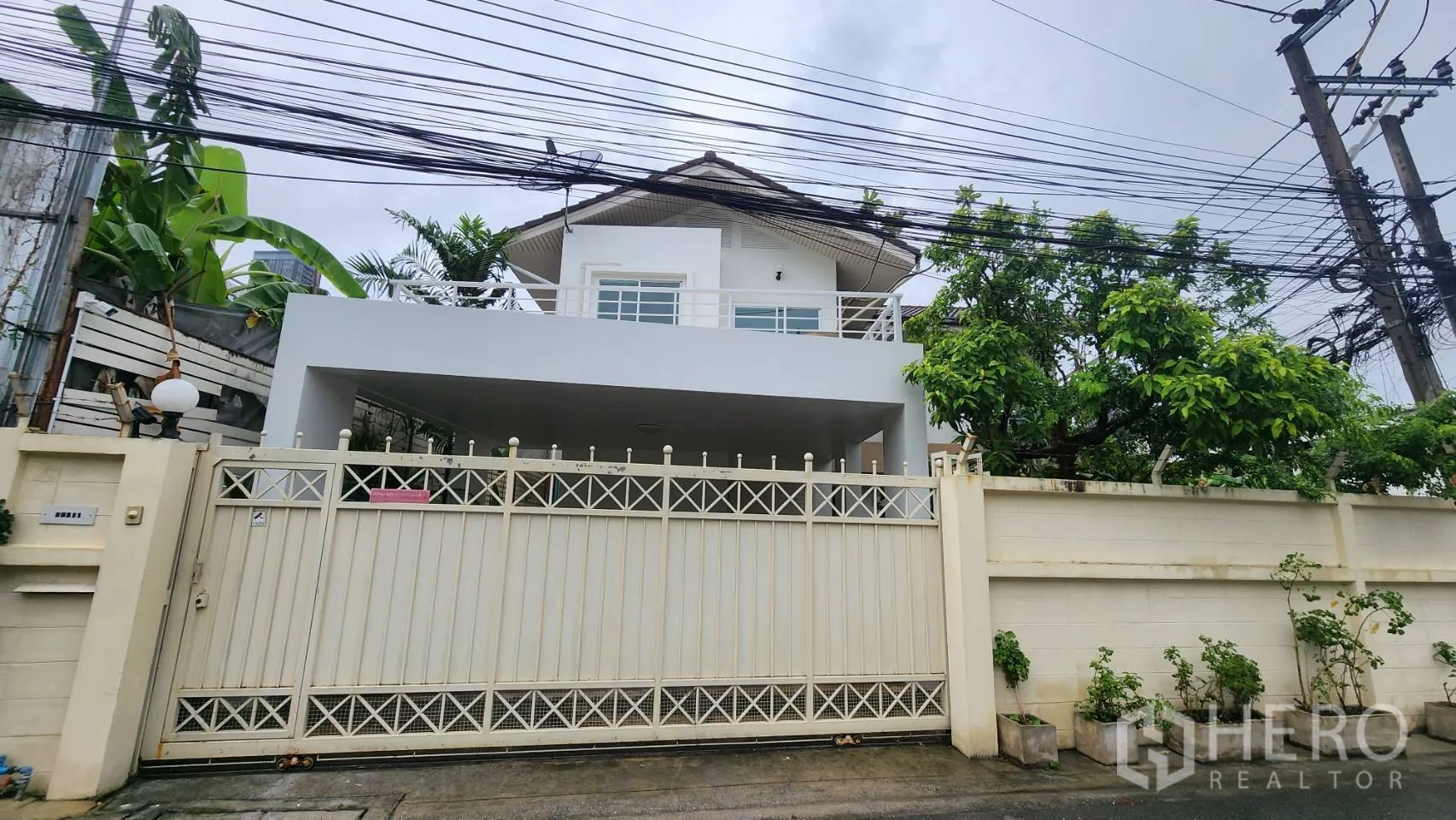 บ้านเดี่ยว for rent in Watthana, Bangkok - ด้านหน้าบ้านพร้อมประตูรั้วทางเข้า โรงจอดรถมีหลังคา และระเบียง