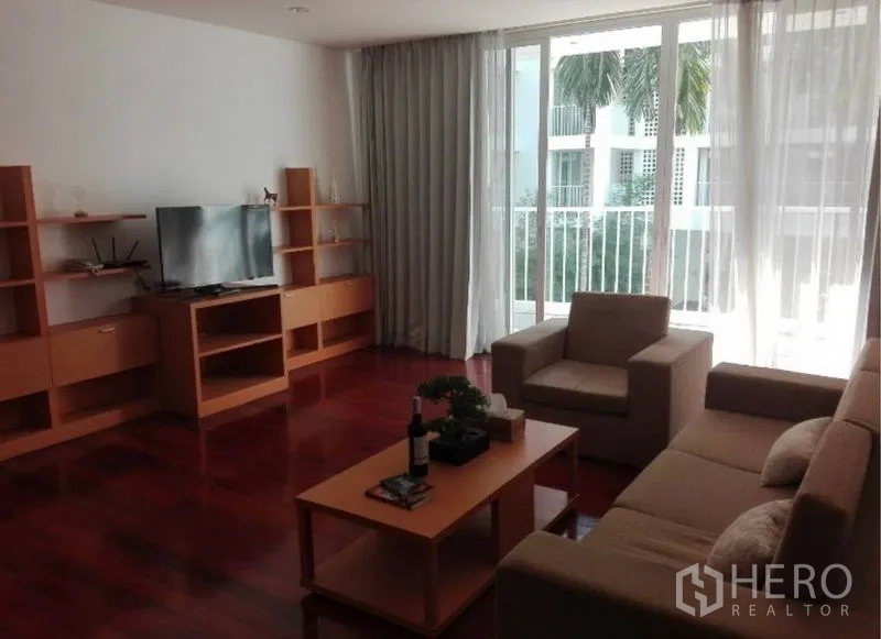 Condominium for rent in Watthana, Bangkok - Living area featuring TV and wood shelving units with a view toward the balcony.