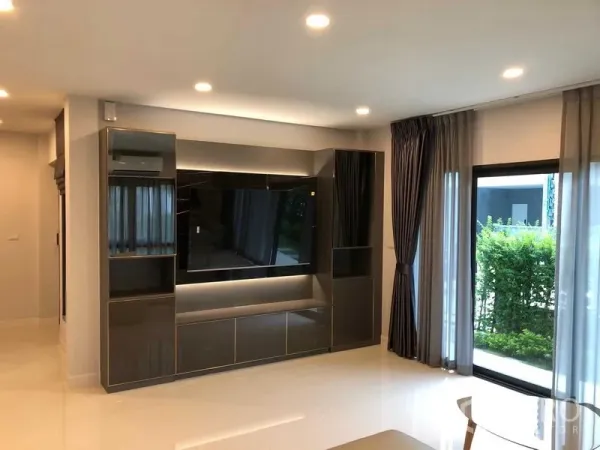 Detached House for rent in Don Mueang, Bangkok - Built-in TV wall with glossy cabinets beside sliding glass doors to the garden.