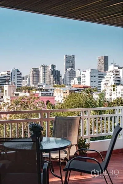 房间 出租在Sathon, Bangkok - 私家阳台配户外餐桌椅，可眺望曼谷城市天际线与绿意社区。