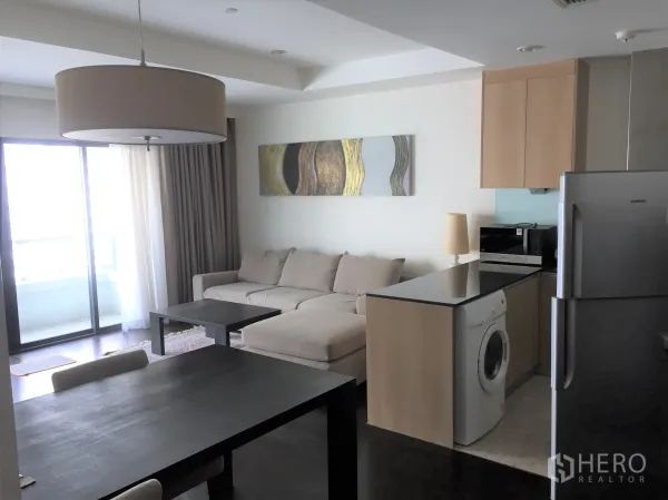 公寓 出租在Sathon, Bangkok - 客餐厅一体，推拉门通向阳台，厨房岛台配洗衣机和不锈钢冰箱。