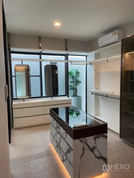 Detached House for rent or sale in Saphan Sung, Bangkok - Bright walk-in closet with island, hanging rails, cabinets and window.