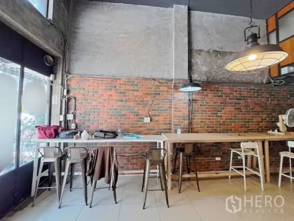 零售空间 出租在Khlong Toei, Bangkok - 沿砖墙的高吧台座位与吊灯，临近落地窗
