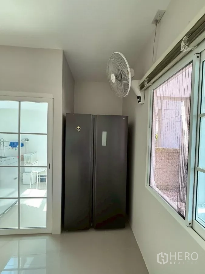 Detached House for rent in Bang Phli, Samut Prakan - Utility nook with double-door refrigerator next to sliding glass door and wall fan.