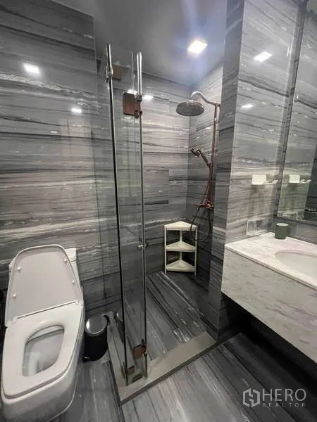 คอนโด ให้เช่าในWatthana, Bangkok - ห้องน้ำลุคโมเดิร์นปูกระเบื้องลายหินสีเทา พร้อมห้องอาบน้ำกระจกแบบเรนชาวเวอร์ อ่างล้างหน้า และโถสุขภัณฑ์
