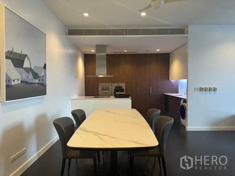 Condominium for rent in Pathum Wan, Bangkok - Open-plan dining and kitchen with island, wood cabinets and a laundry area.