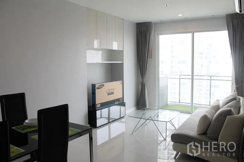 Condominium for rent or sale in Watthana, Bangkok - Open living and dining space leading to a balcony, glossy tile floors, and built-in cabinetry.